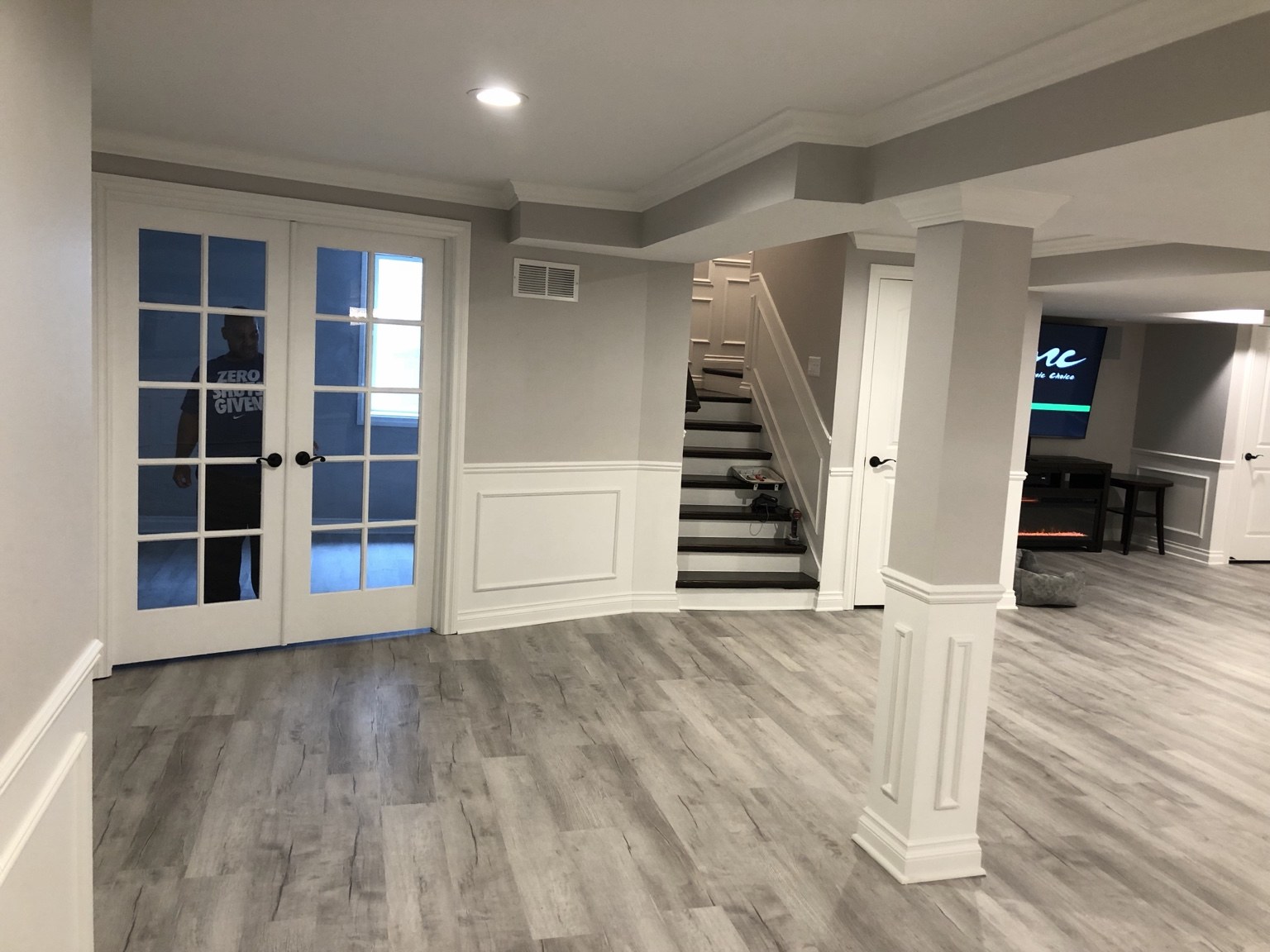Finished basement with French doors, staircase, and custom white trim