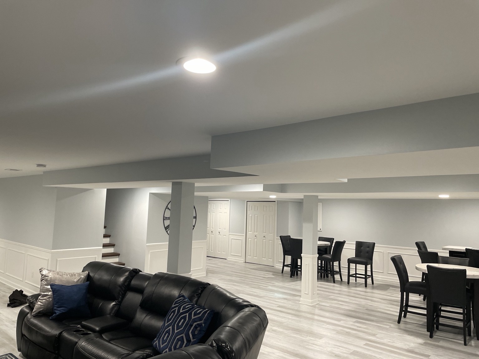 Finished basement lounge with paneled walls and light wood-look flooring