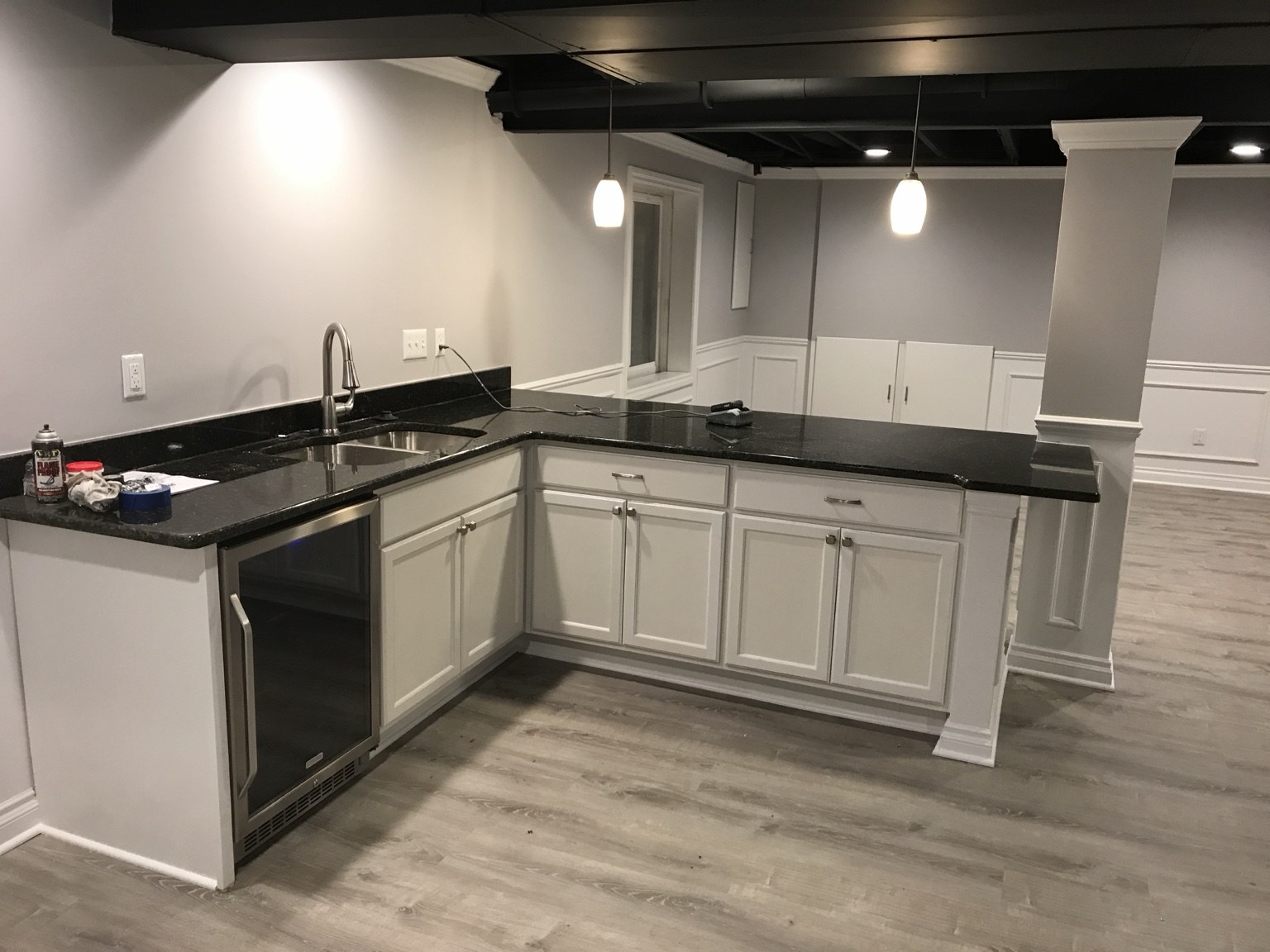 Basement wet bar with white cabinets and dark countertops