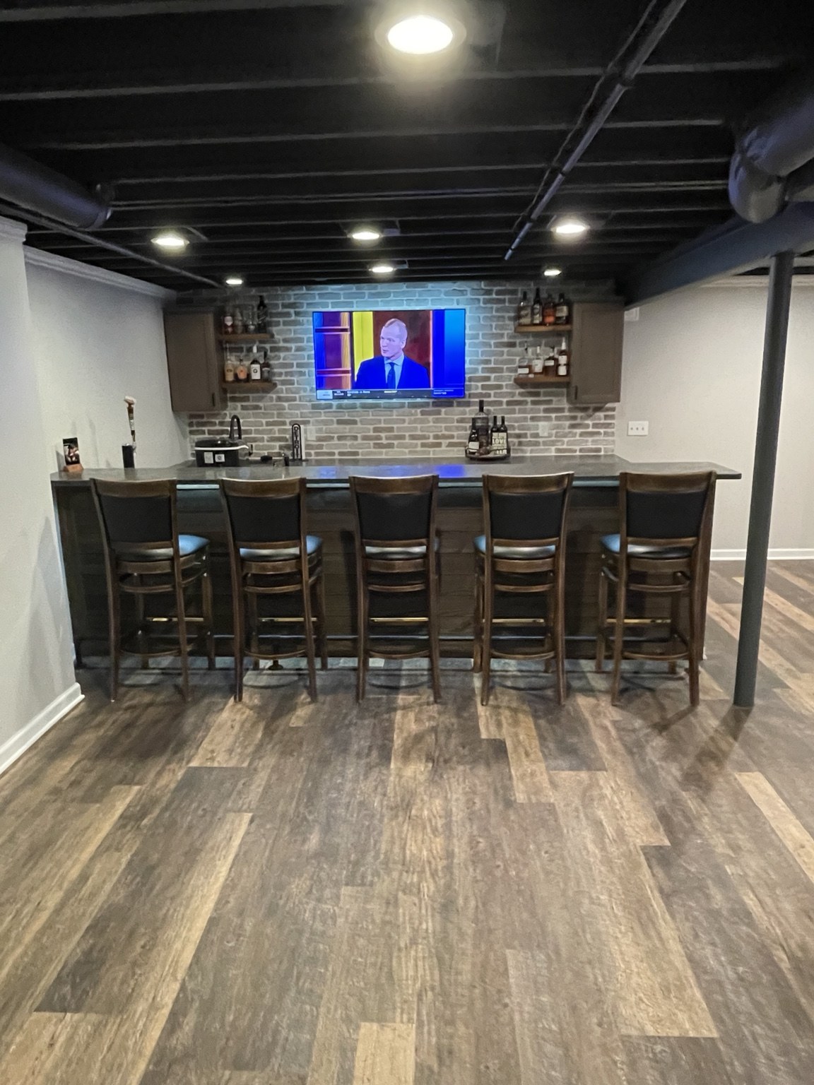 Basement bar with seating and a black exposed ceiling