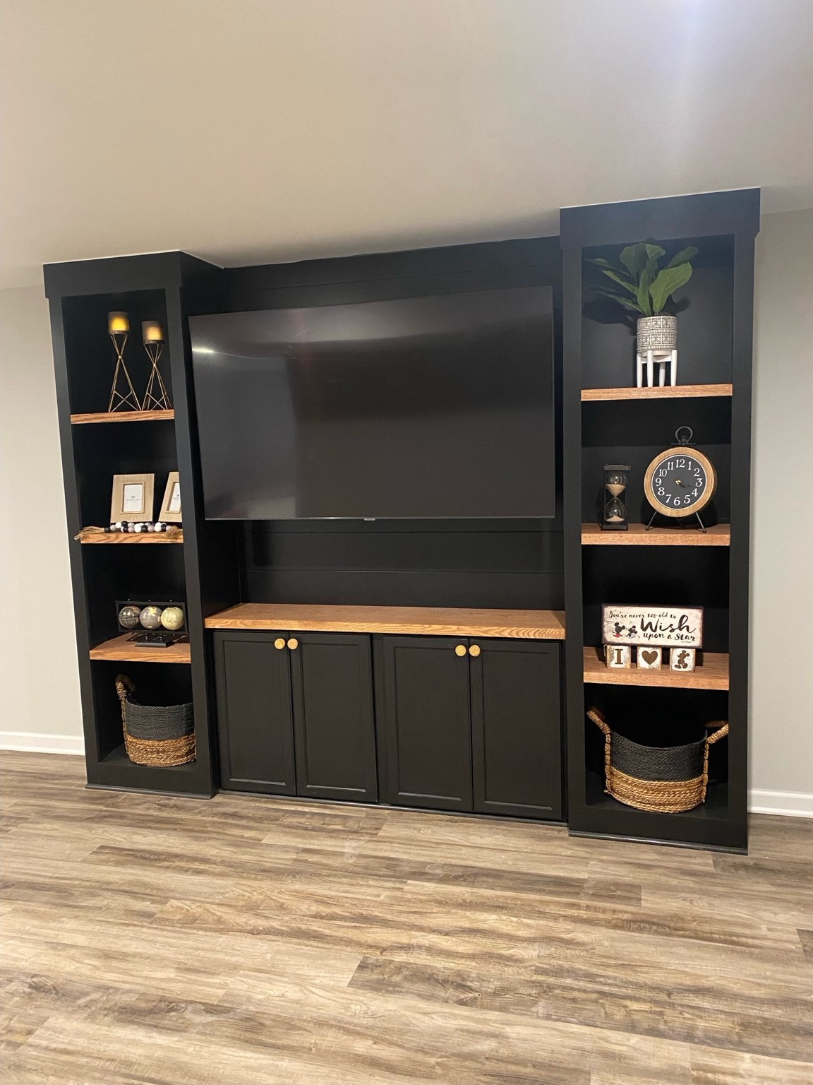 Custom basement entertainment center with dark cabinetry and shelving