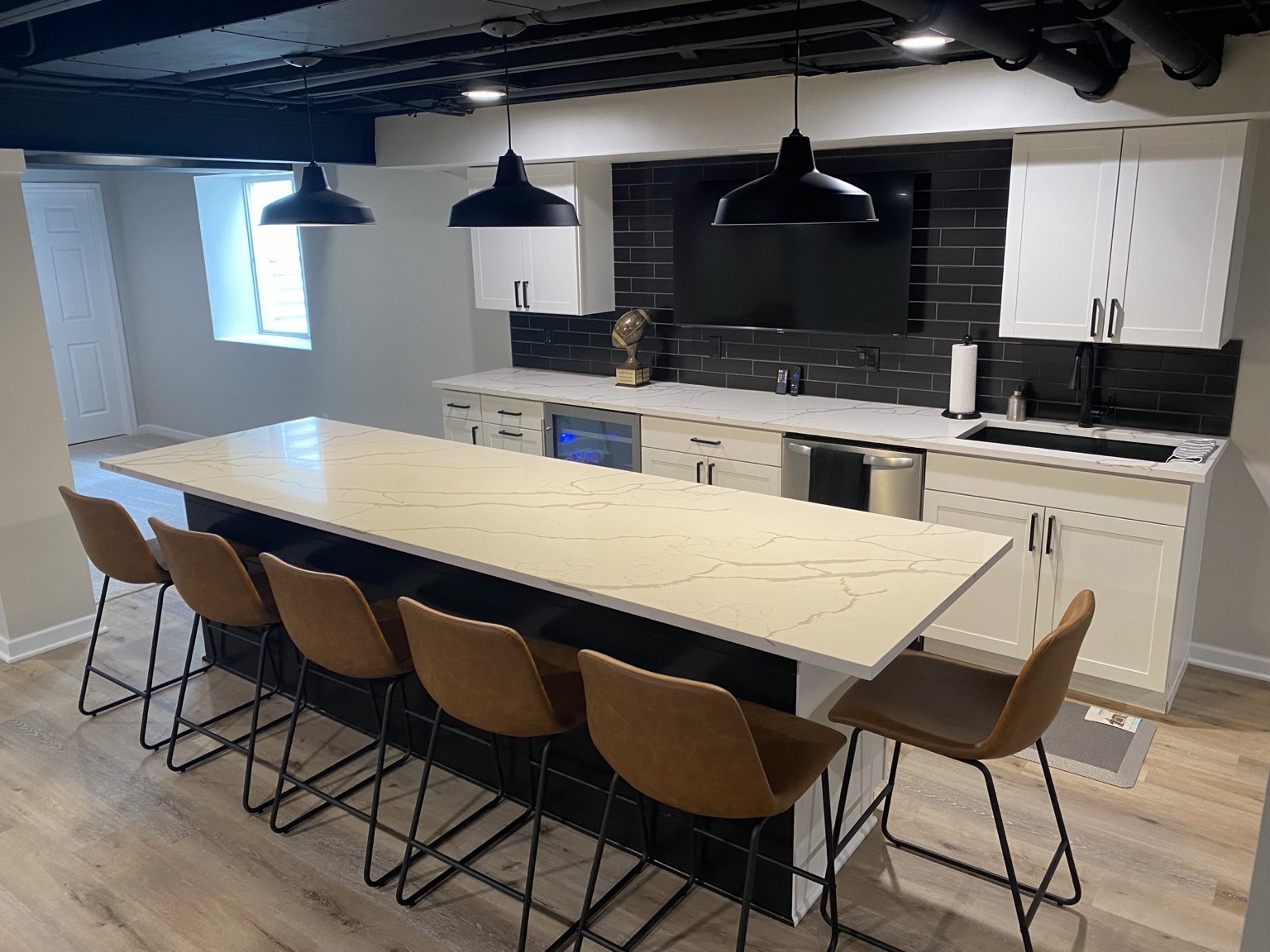 Custom basement bar with black tile backsplash and countertop seating