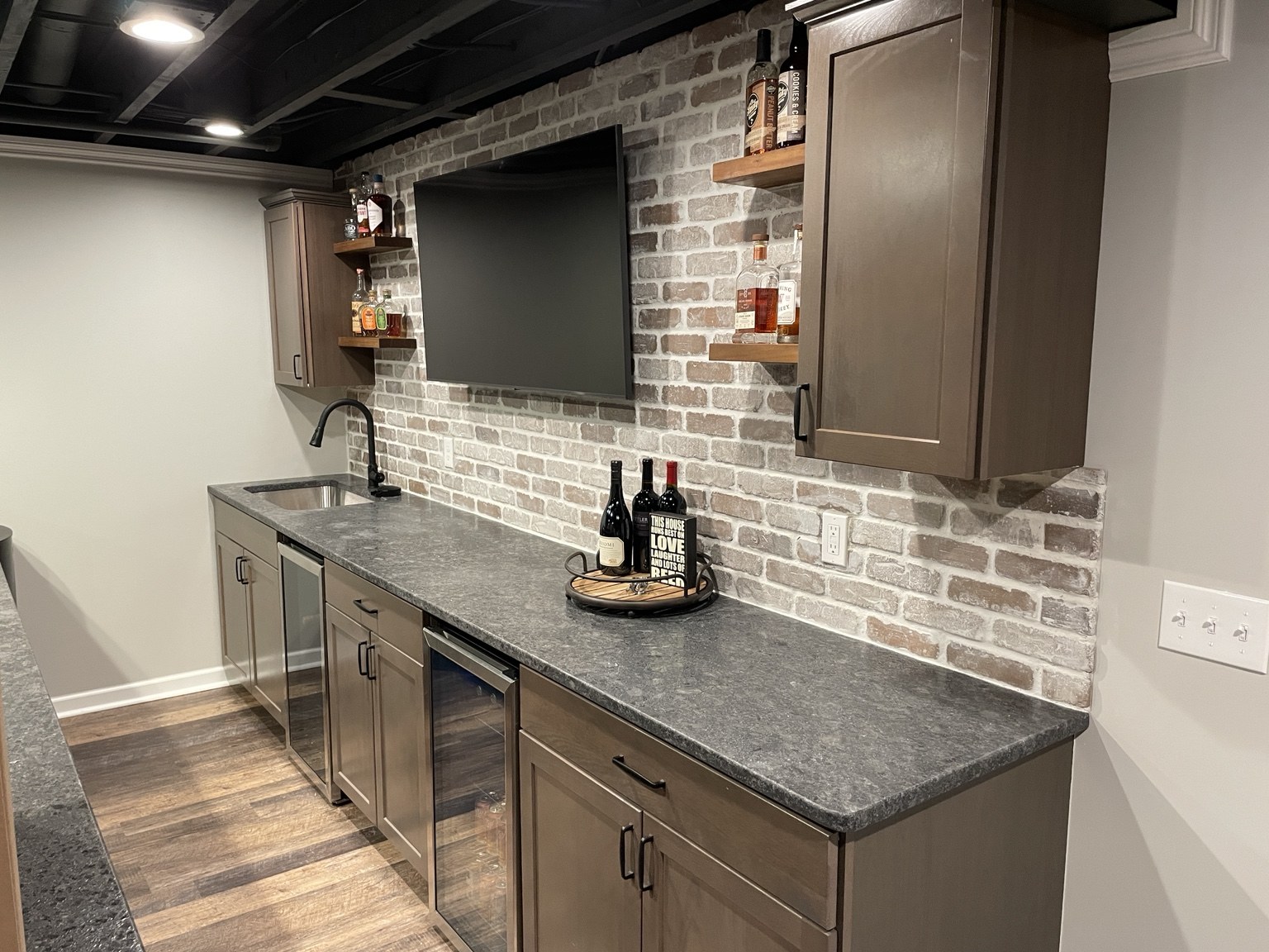 Custom basement wet bar with brick backsplash and cabinetry