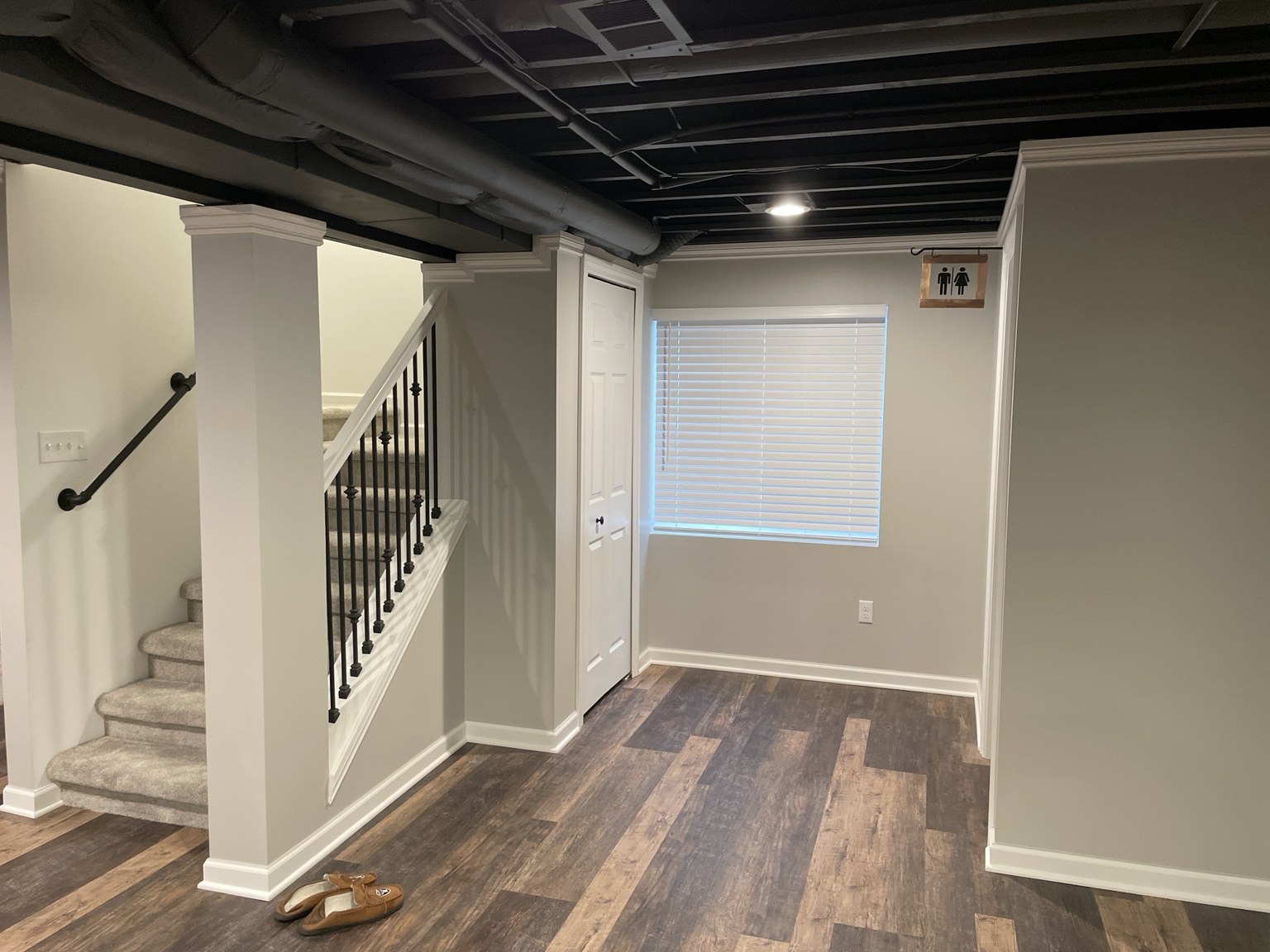 Finished basement staircase with white trim and wood-look flooring
