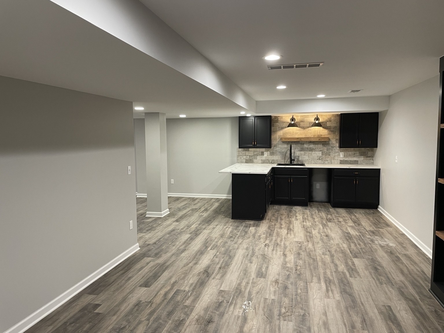 Open finished basement with wood-look flooring and wet bar