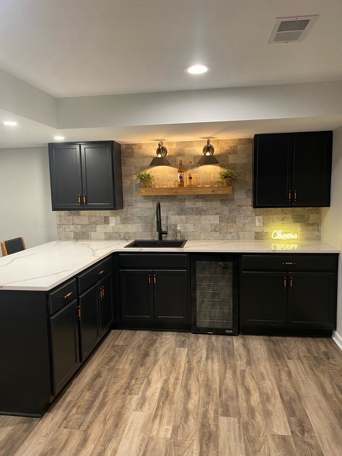 Basement wet bar with dark cabinetry and illuminated backsplash