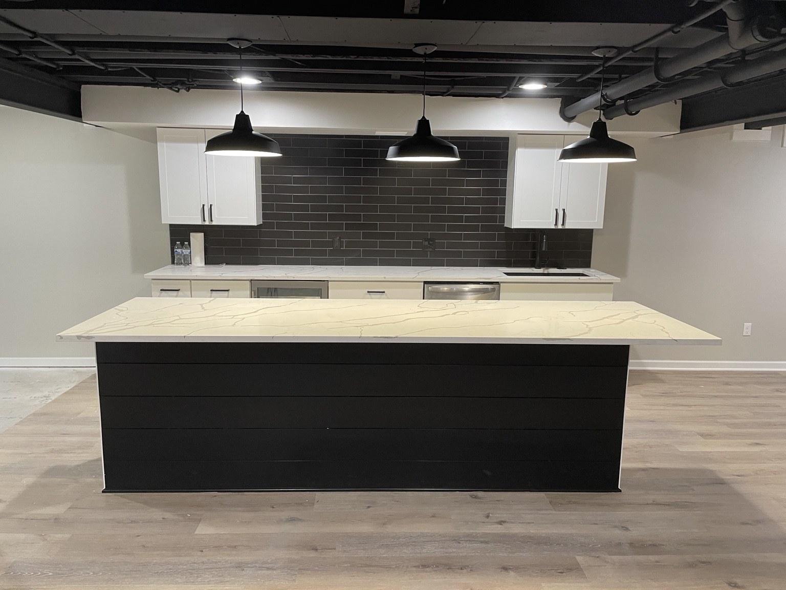Basement bar with island and black exposed ceiling