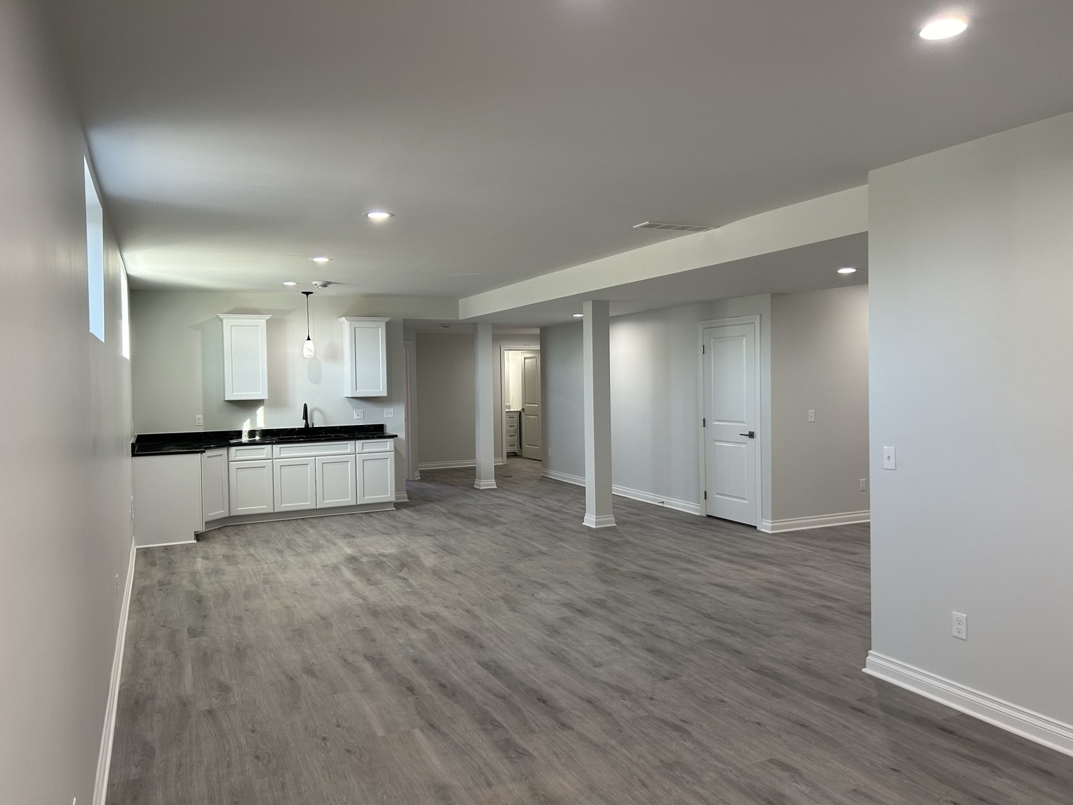 Open basement living area with white wet bar cabinets
